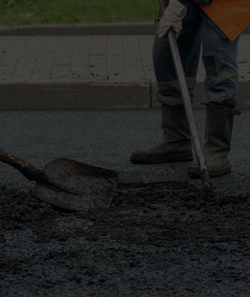 Worker repairing road with asphalt.