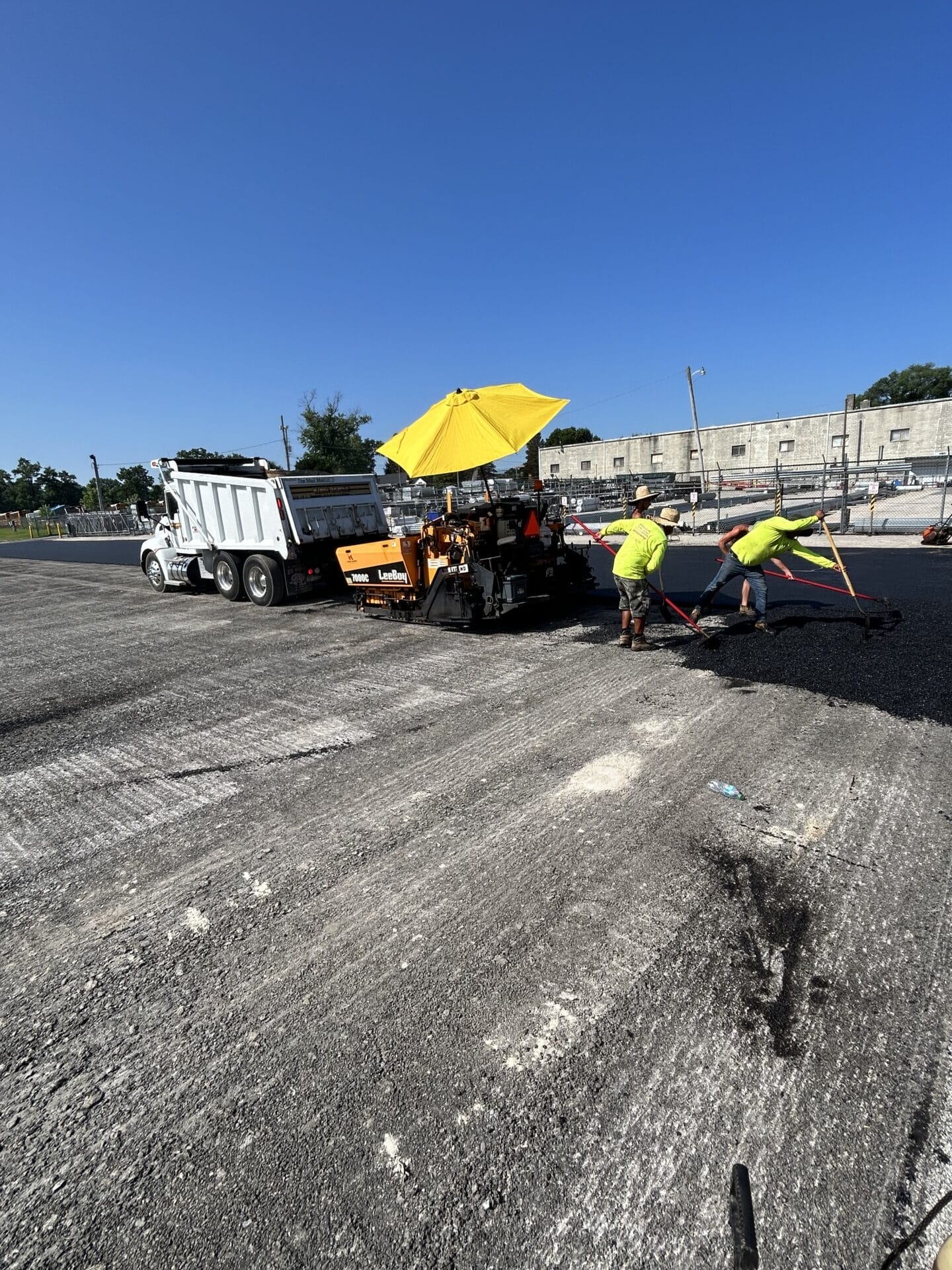 Workers paving asphalt under sunshade